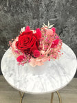 Bouquet of dried flowers with eternal red rose and pink hydrangea stabilized in its small vase, wedding centerpiece